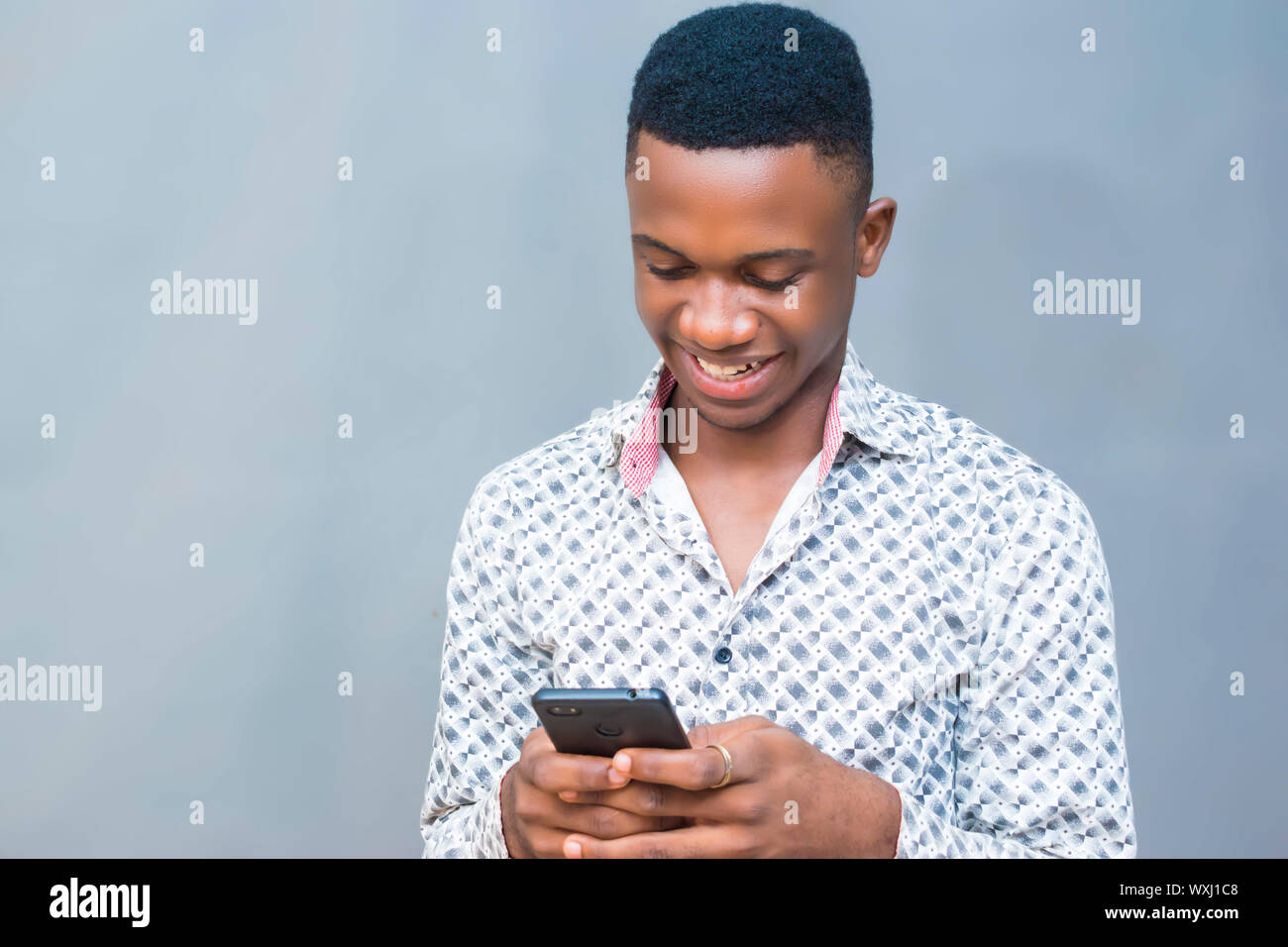 nero africano giovane hipster sorridente utilizzando il telefono cellulare, la lettura di testo, la navigazione in internet, la visione di video online Foto Stock