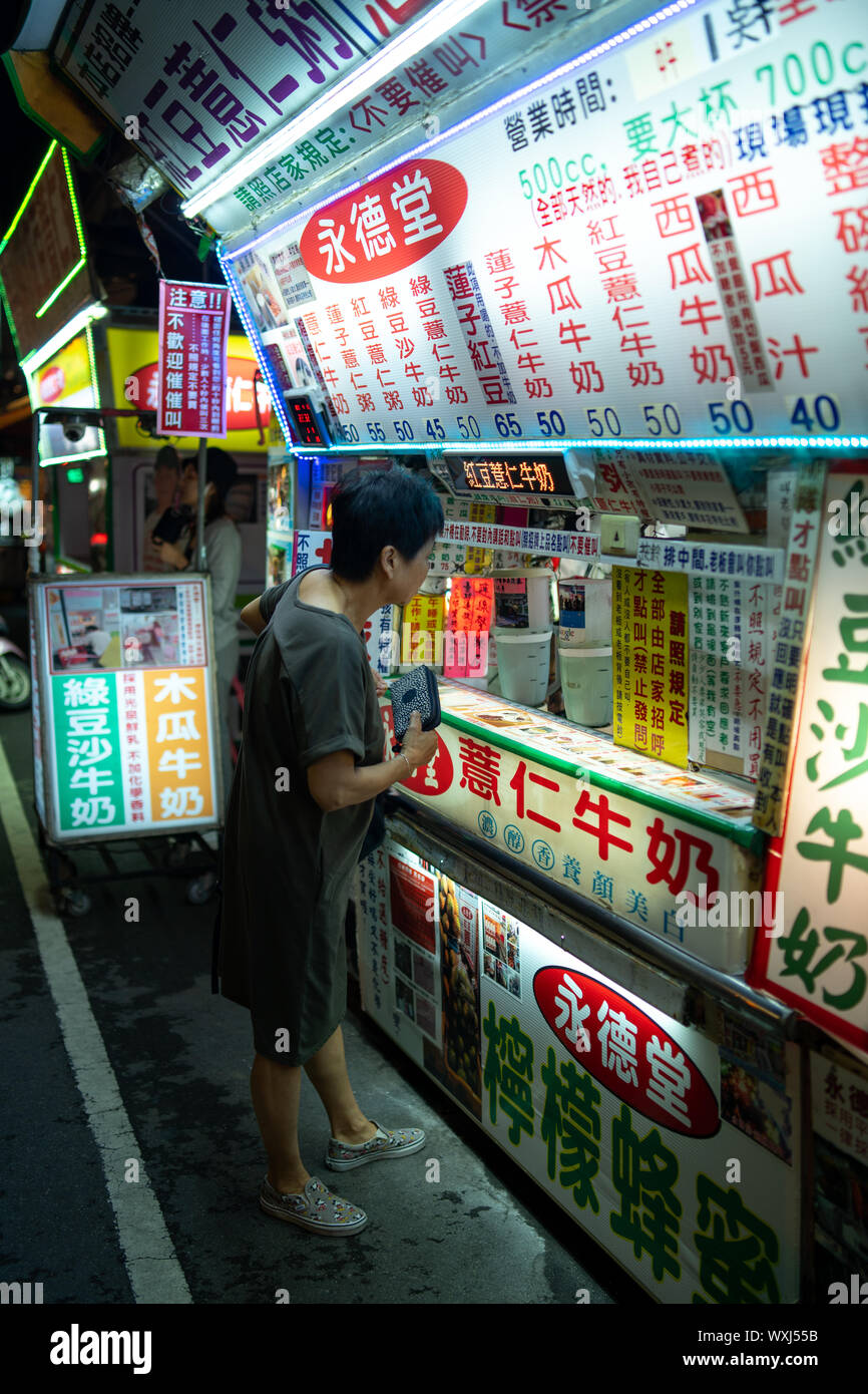 Taichung, Taiwan: piccola cucina di strada fornitore con una enorme scelta di vendere un varietà di latte e bevande base frutta in un mercato notturno. Le donne acquistare bevande Foto Stock