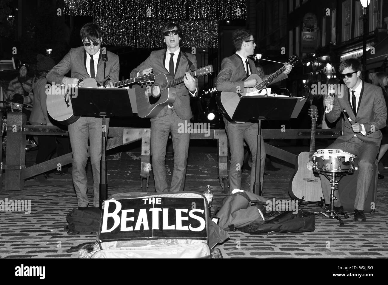 Un Beatles tribute band suonare le canzoni dei Beatles sulle strade di Covent Garden, Londra WC2. Autentica le immagini in bianco e nero. I BEATLES. La musica. Bande tributo. Buskers. Musicisti. Licenza buskers. Foto Stock