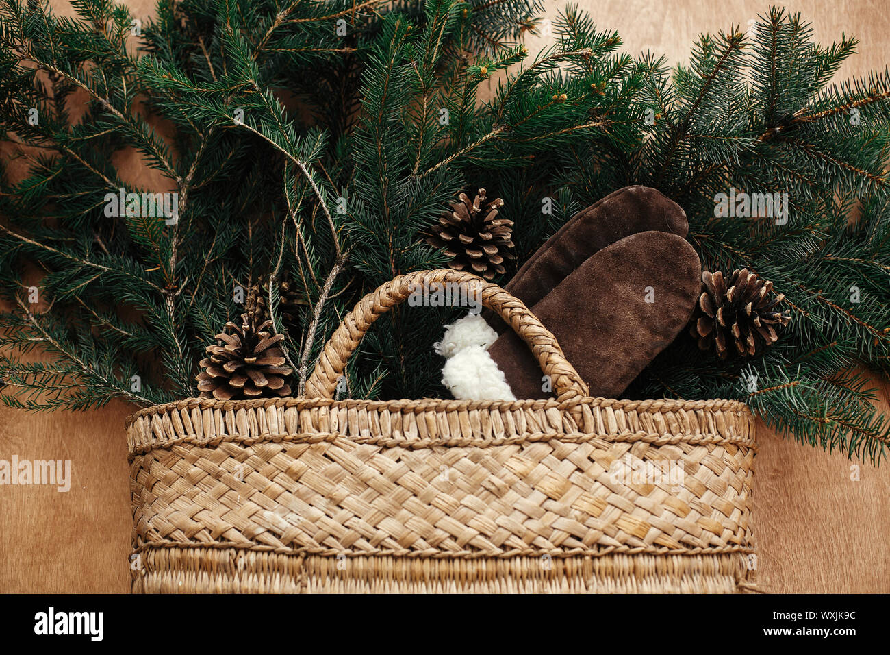 Cesto rustico con rami di abete, intimo guanti, coni in legno rustico sfondo. Lay piatto. Vacanze invernali preparati. I migliori auguri di Buon Natale Foto Stock