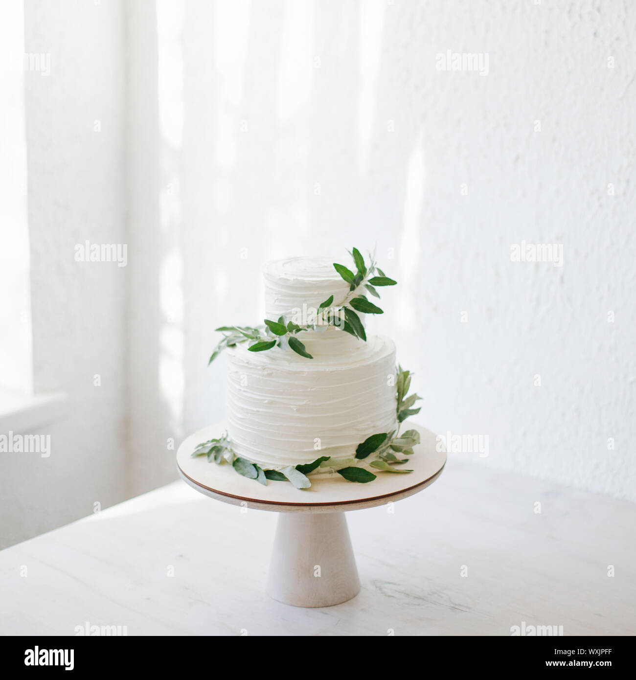 Due tiered torta nuziale con glassa e olive branch decorazione Foto Stock