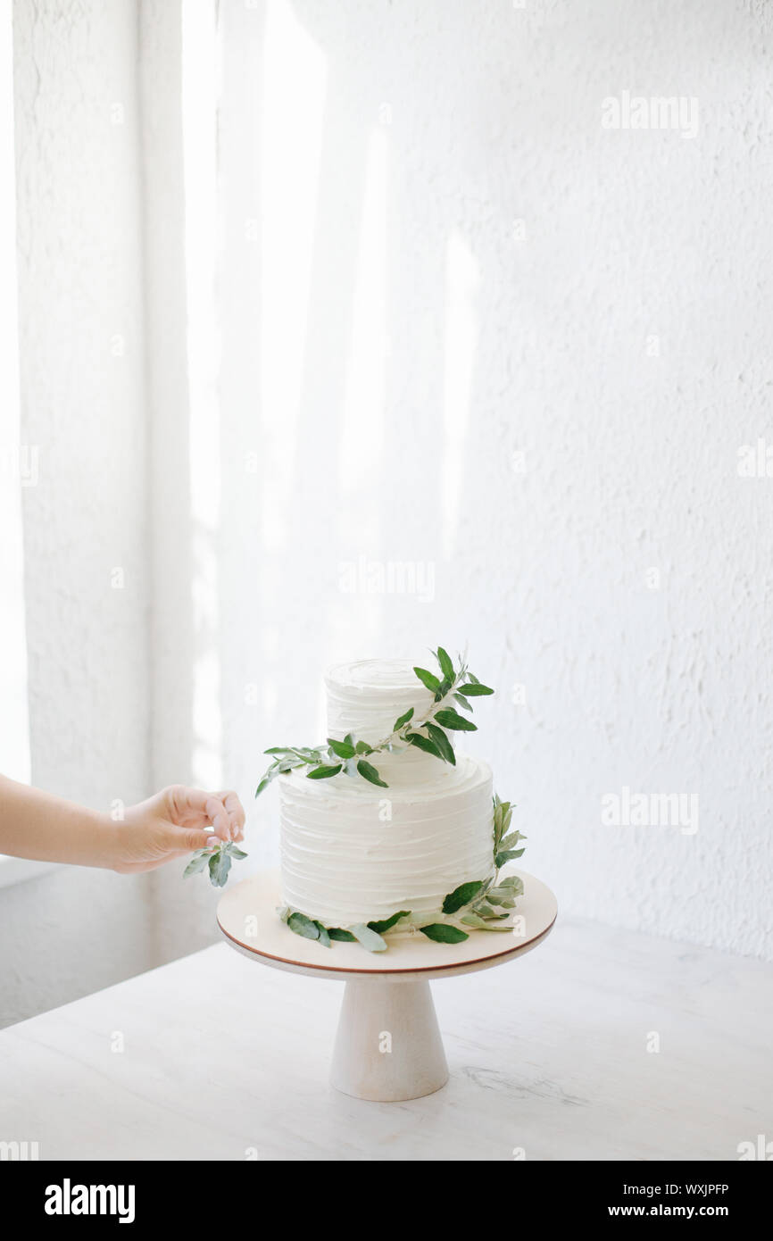 Donna decorare un due tiered torta di nozze con rami di olivo Foto Stock