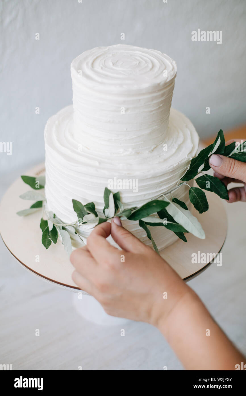 Donna decorare un due tiered torta di nozze con rami di olivo Foto Stock