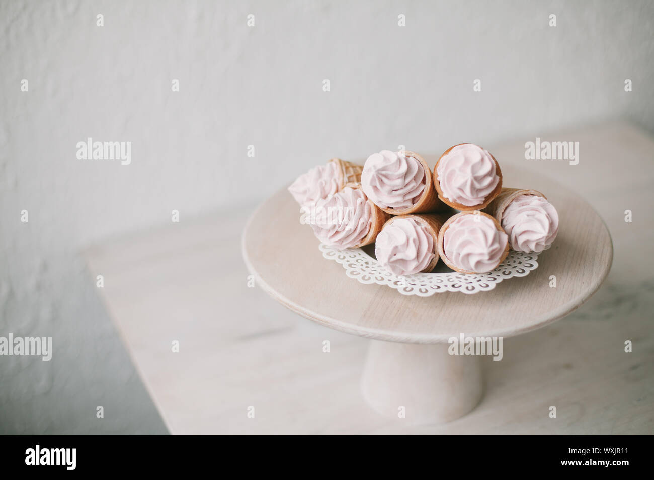 Coni cialde farcito con panna montata su un cakestand Foto Stock