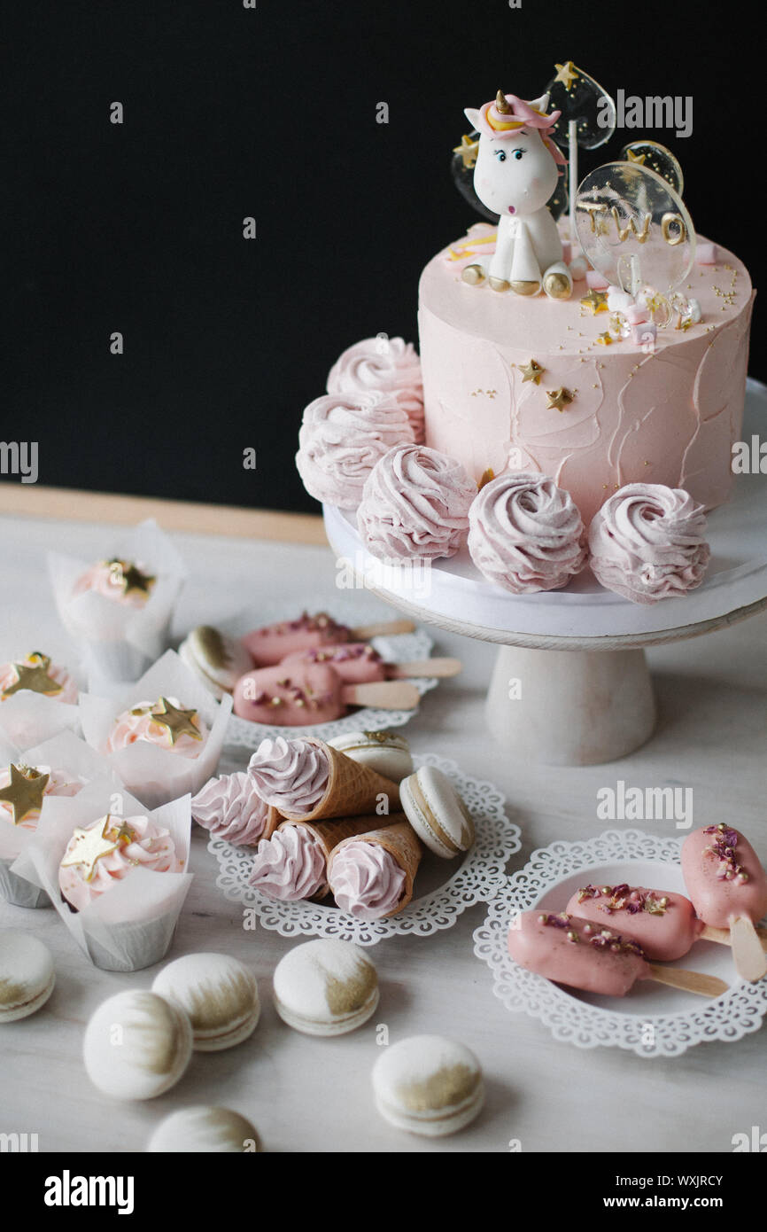 Unicorn torta di compleanno con tortine, coni di cialda con crema, torta gelato pop e amaretti Foto Stock