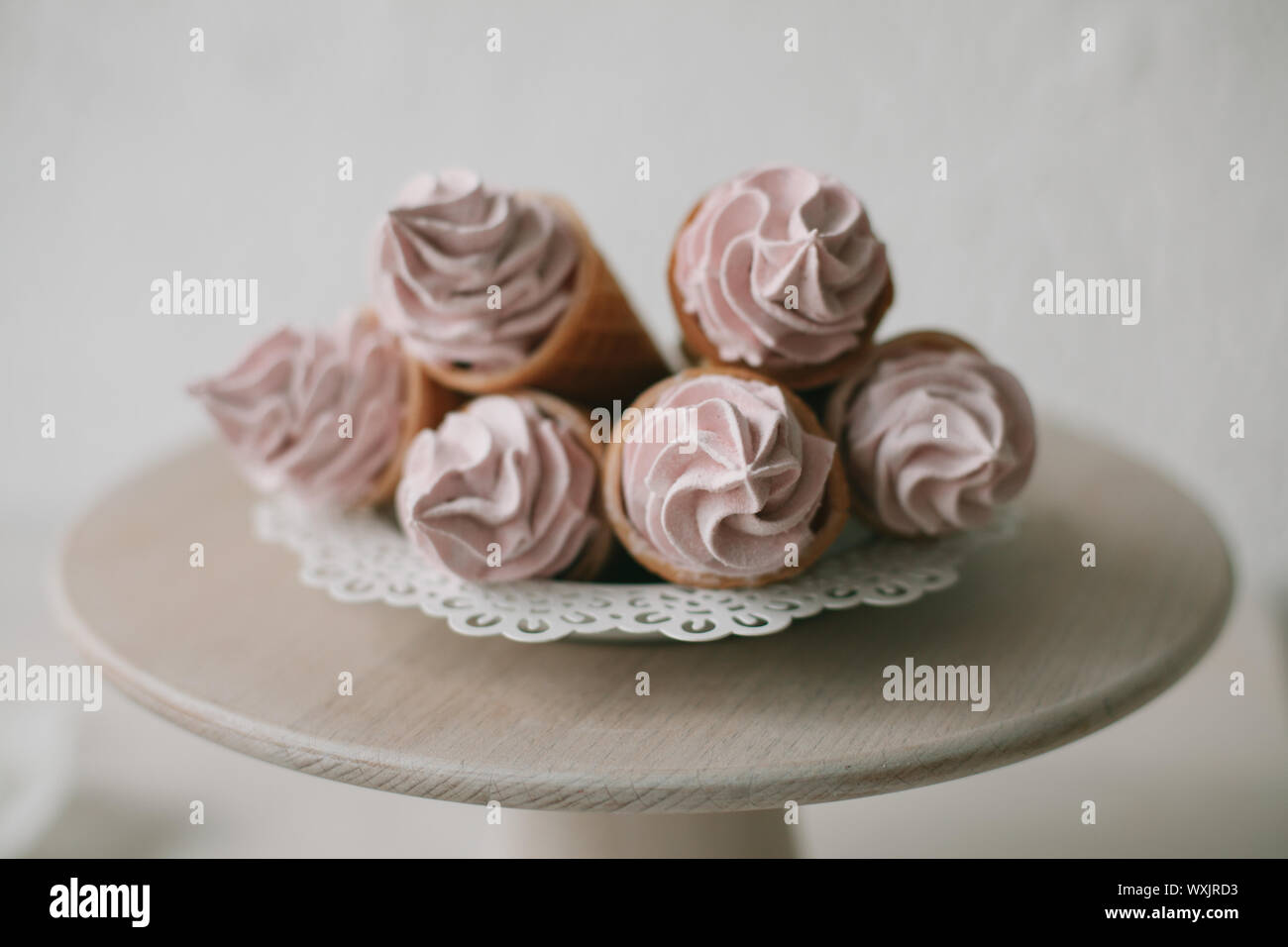 Coni di cialda farcito con panna montata su un cakestand Foto Stock