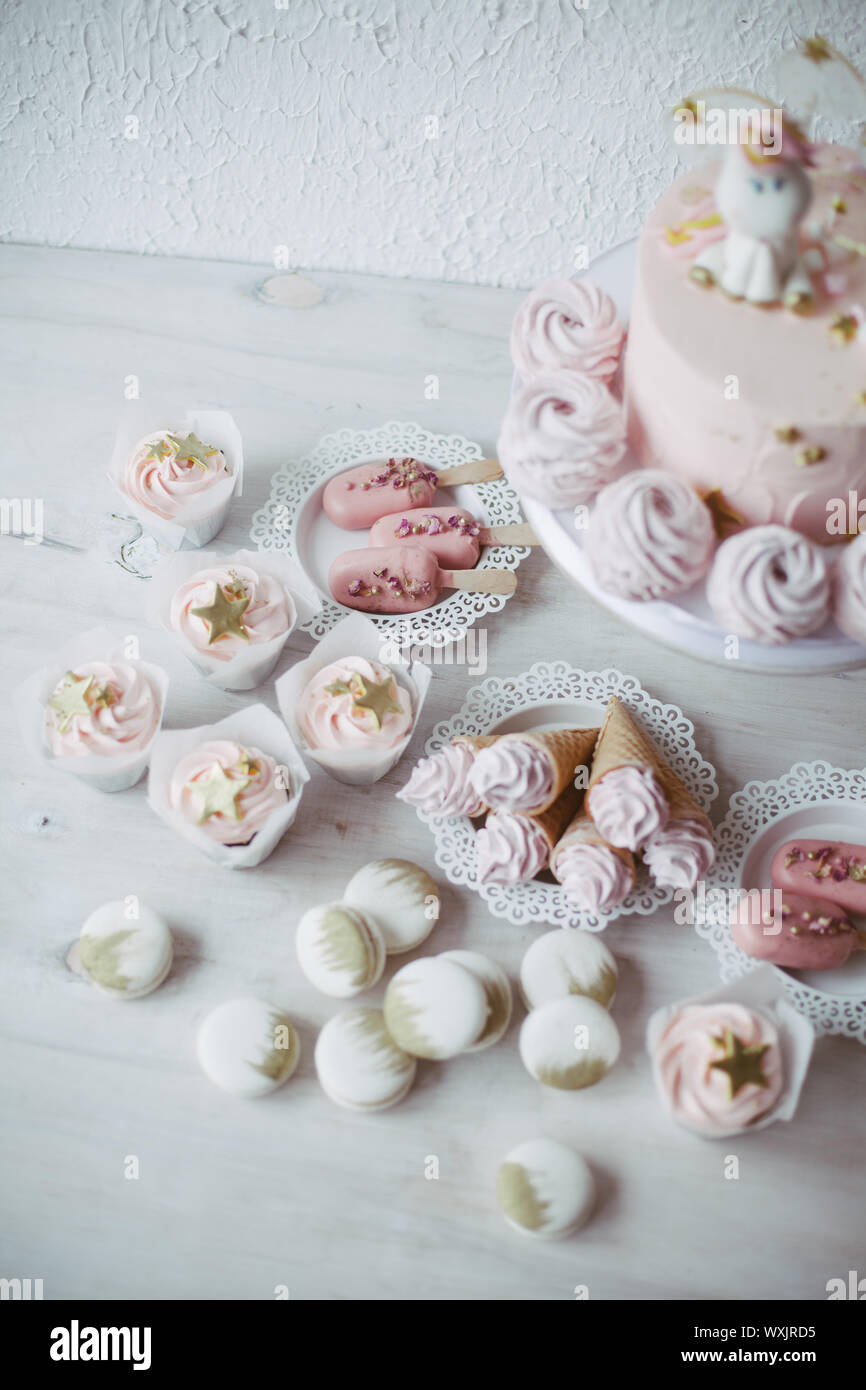 Unicorn torta di compleanno con tortine, coni di cialda con crema, torta gelato pop e amaretti Foto Stock