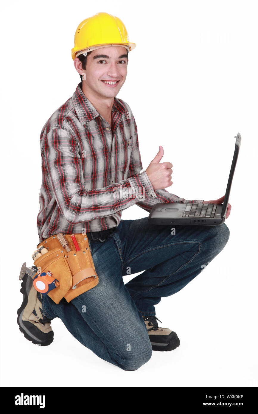 Happy builder con laptop dando il pollice in su Foto Stock