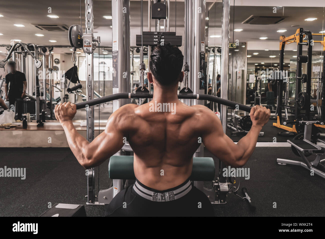 Montare l'uomo sul lat pulldown macchina presso il club benessere. Lavorare sul peso Pulldown macchina Foto Stock