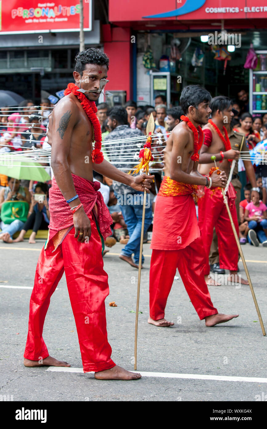 Kavadi indù ballerini con perforazioni attraverso la loro guance e ganci attraverso le loro spalle eseguire lungo una strada, Kandy, Sri Lanka durante il giorno Perahera. Foto Stock