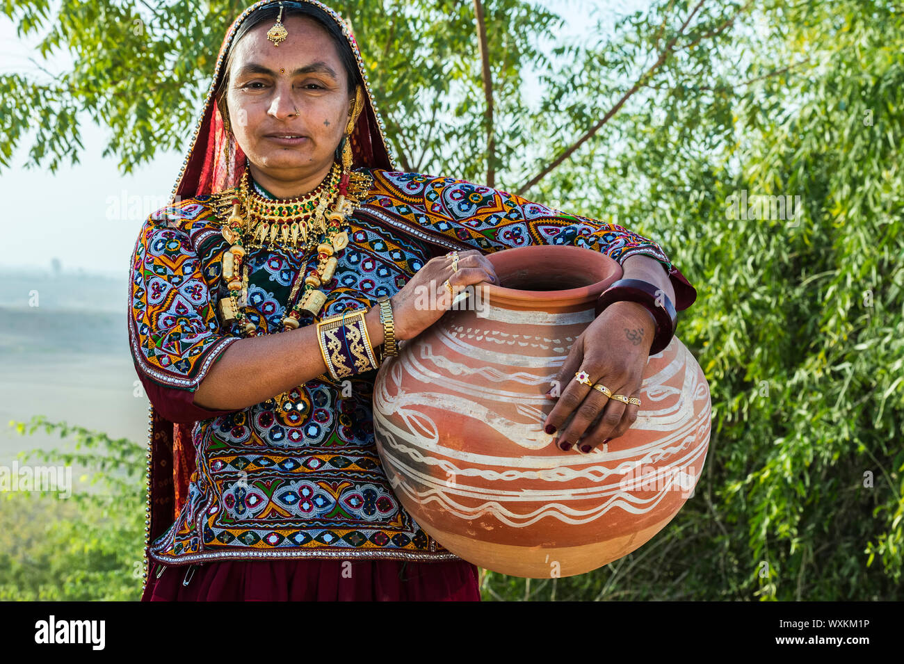 Ahir donna nel tradizionale tessuto colorato che trasportano acqua in una brocca di argilla, grande Rann di Kutch deserto, Gujarat, India Foto Stock