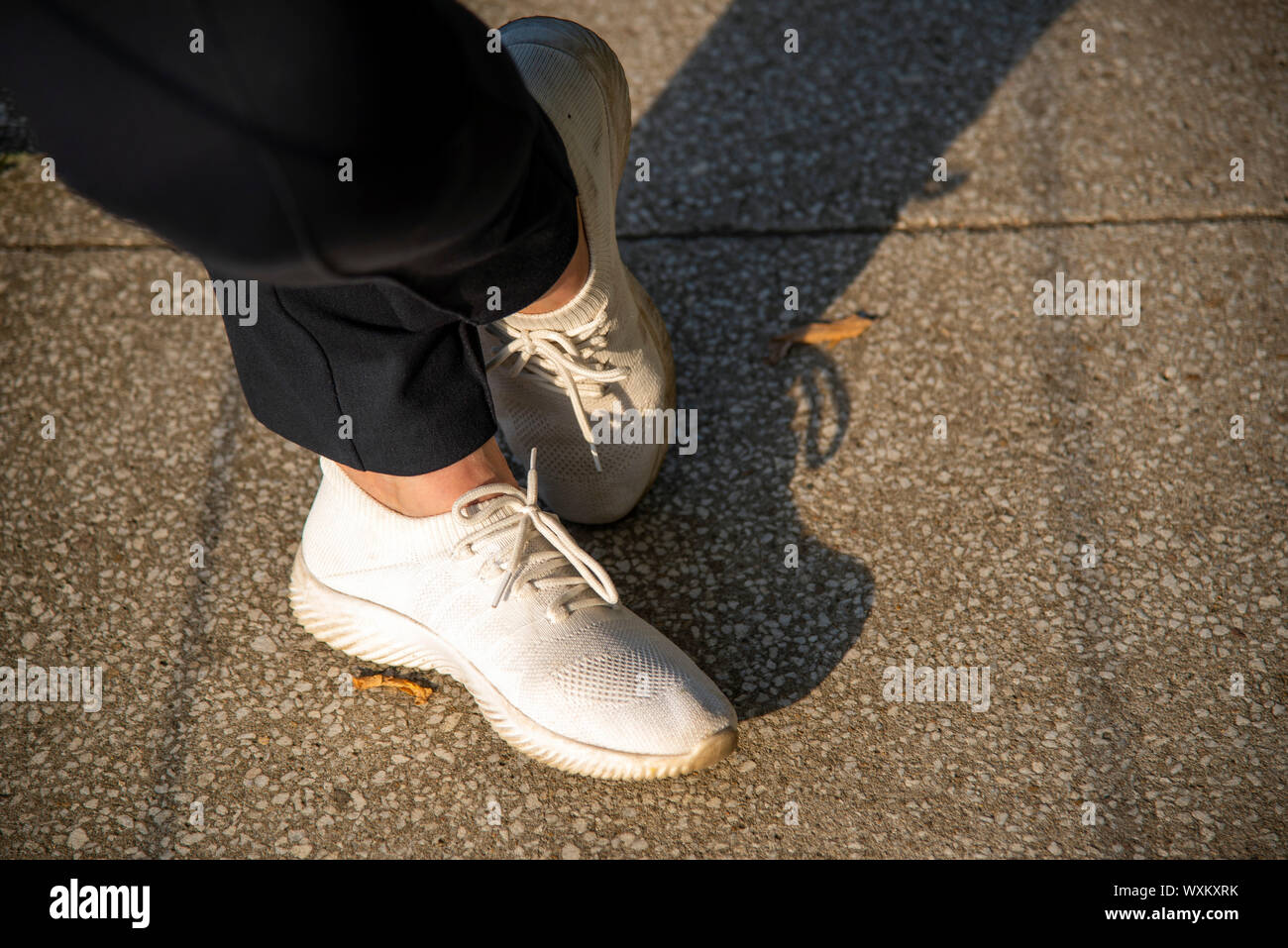 Piedi in sport pantaloni neri e bianco sneakers Foto stock - Alamy
