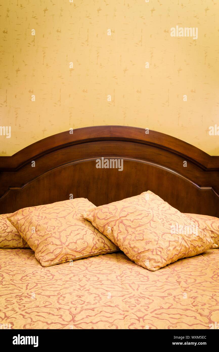 Letto matrimoniale con biancheria da letto contro una parete di camera da letto, ideale per copyspace Foto Stock