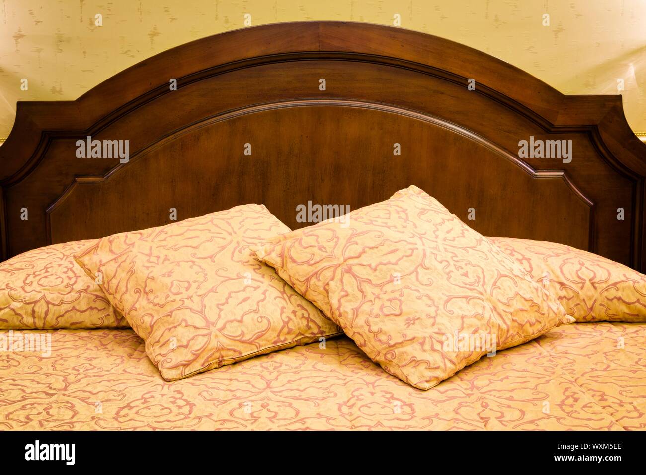 Camera da letto interno di un tradizionale letto con testiera, cuscini e guanciali Foto Stock