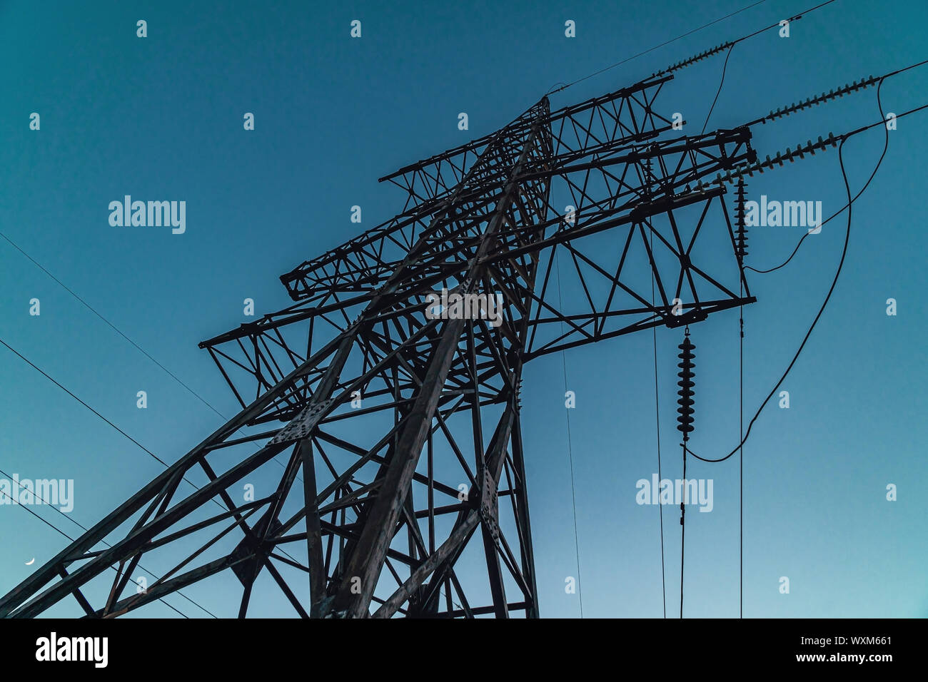 Le linee di alimentazione sul traliccio metallico sopra il cielo blu Foto Stock