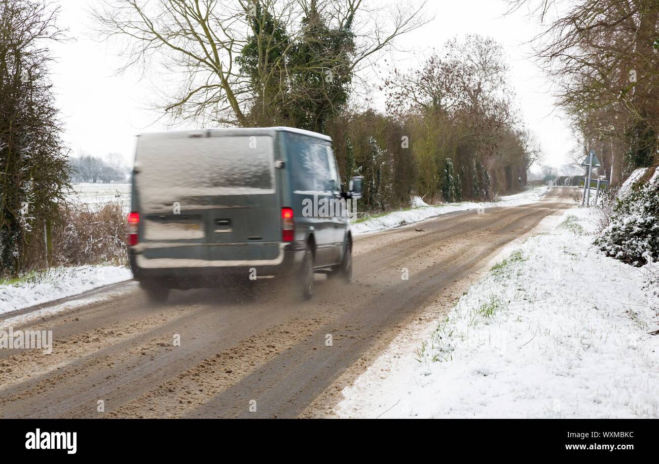 Il transito van la guida in presenza di neve in inverno su un isolato strada rurale nella campagna inglese. Inghilterra, Regno Unito Foto Stock