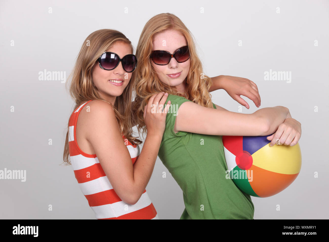 Due adolescenti indossando occhiali da sole tenendo palla spiaggia Foto Stock