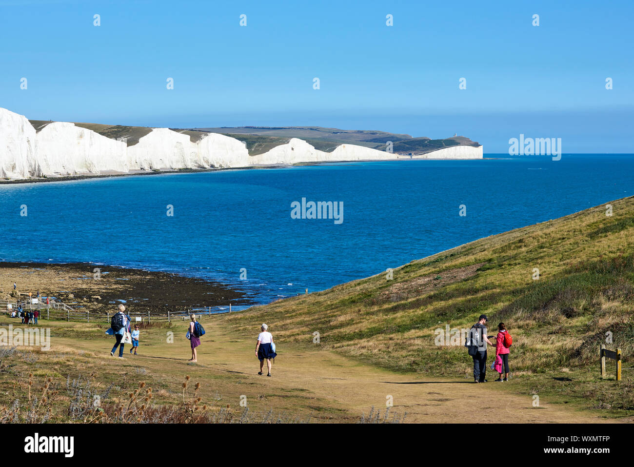 Walkers sul South Downs a Seaford Testa, vicino a Eastbourne, East Sussex, guardando ad est verso le sette sorelle scogliere Foto Stock