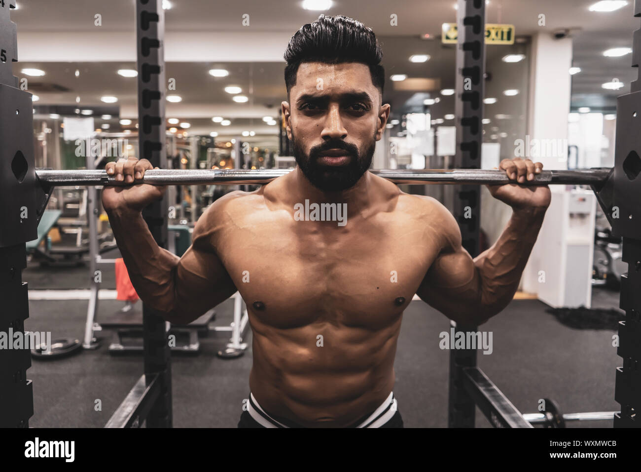 Uomo in palestra. Eseguire esercizio squatting con peso in palestra Foto Stock