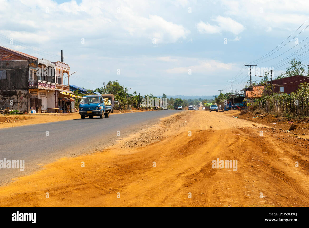 A Pakse, Laos - Feb 2016: Strada con pochi i veicoli che attraversano la campagna in Laos Foto Stock