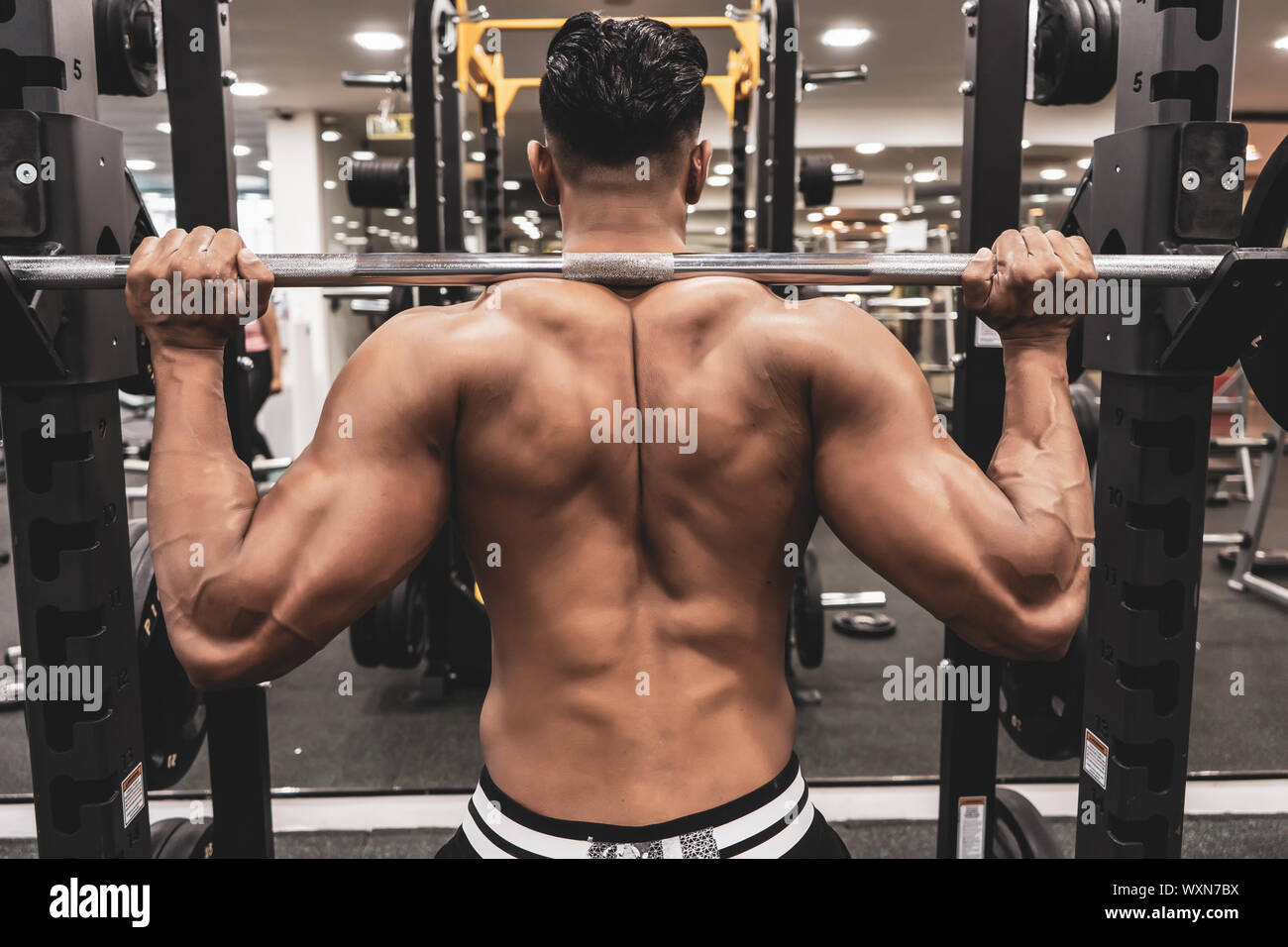 Uomo in palestra. Eseguire esercizio squatting con peso in palestra Foto Stock