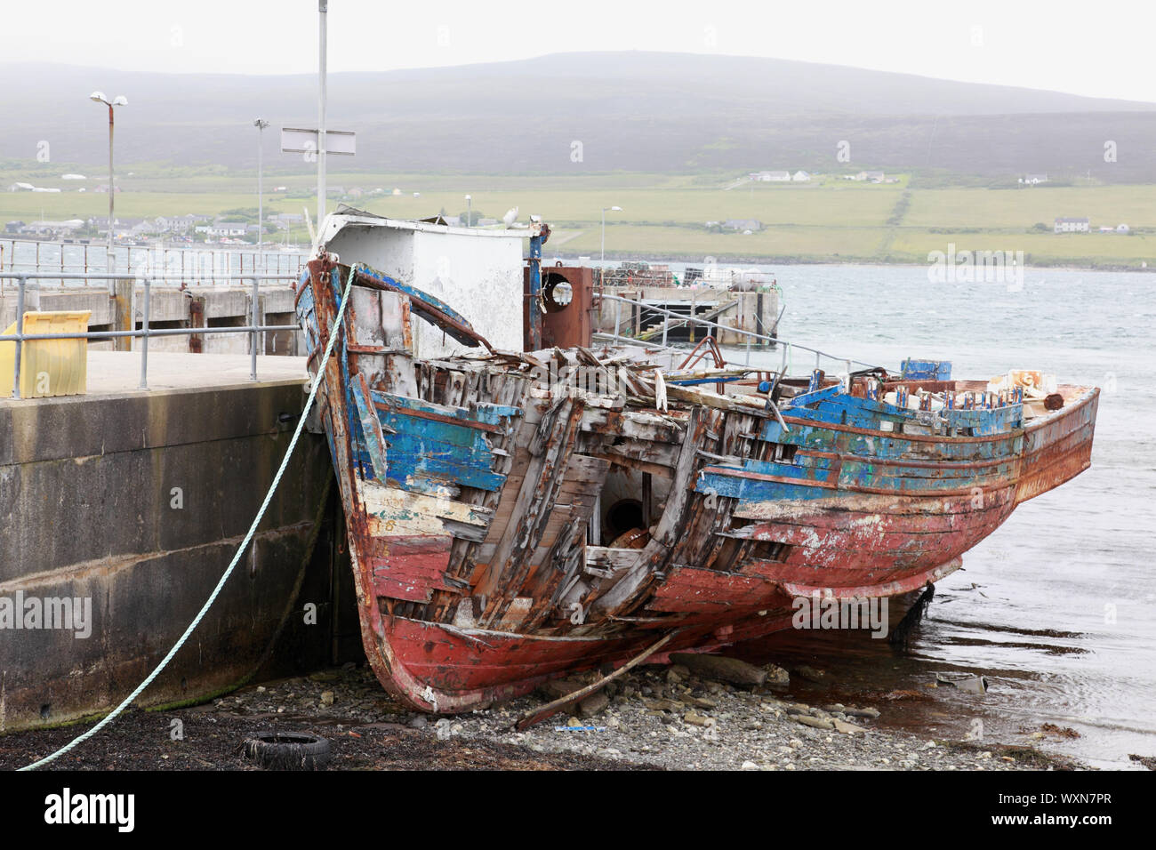 Una barca da pesca marciume lontano dal porto Molo Wyre, Orkney Islands, rivolto verso l'isola di Rousay Foto Stock