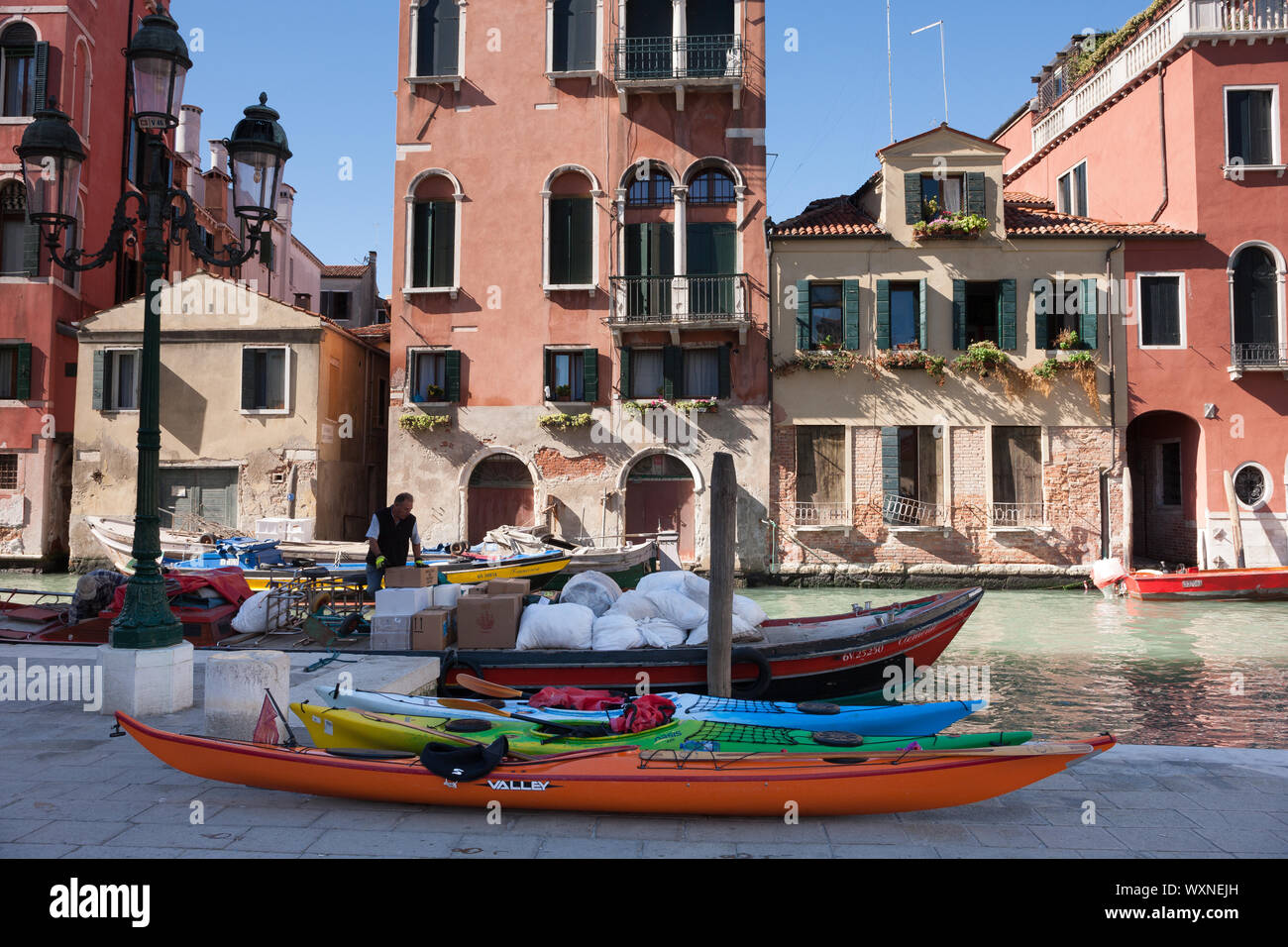 Canale di Venezia con una barca a motore d'acqua davanti a vecchi edifici Foto Stock