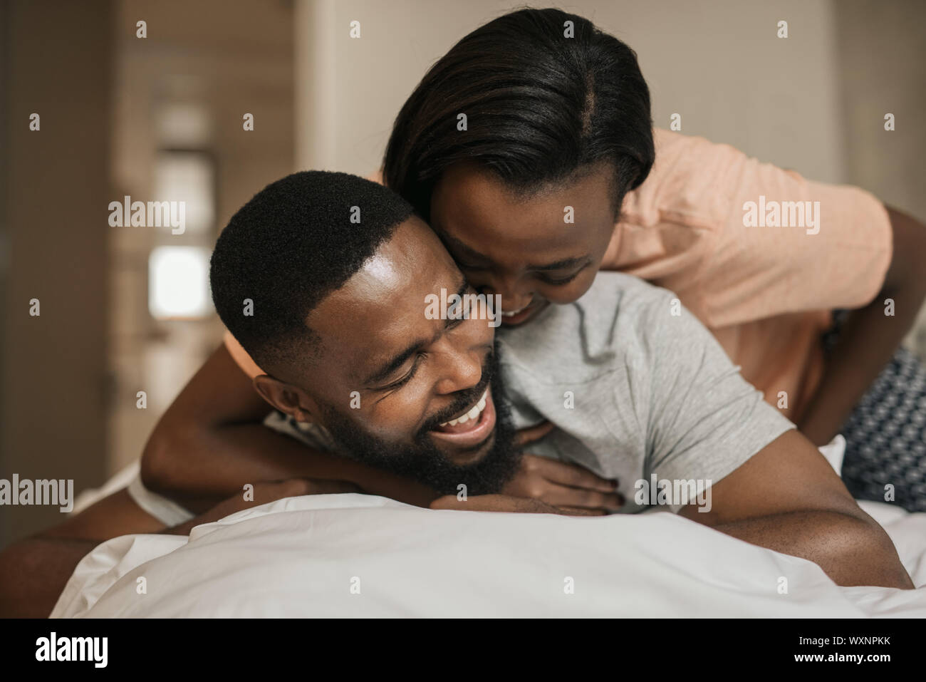 Ridendo giovane africano coppia americana giocando a letto insieme Foto Stock