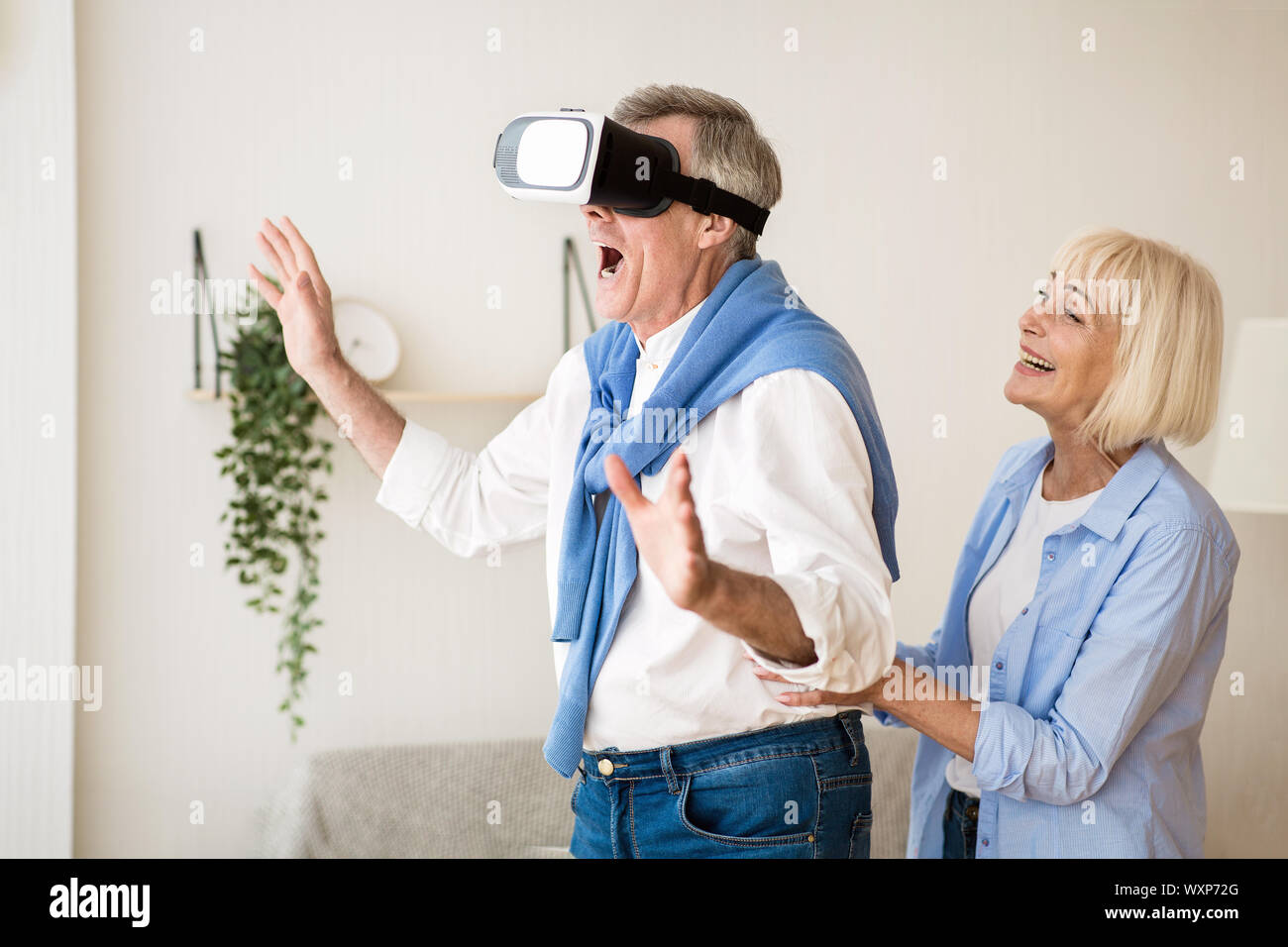 Uomo maturo utilizzando occhiali VR, divertendosi a casa Foto Stock