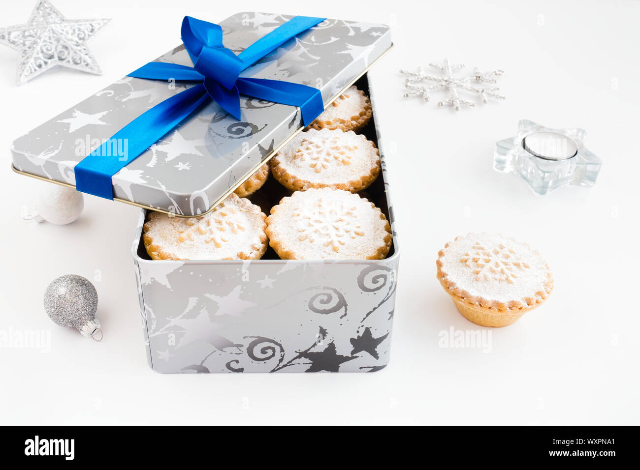 Primo piano di pasticci di carne macinata in cookie tin con decorazione di Natale su sfondo bianco. Foto Stock