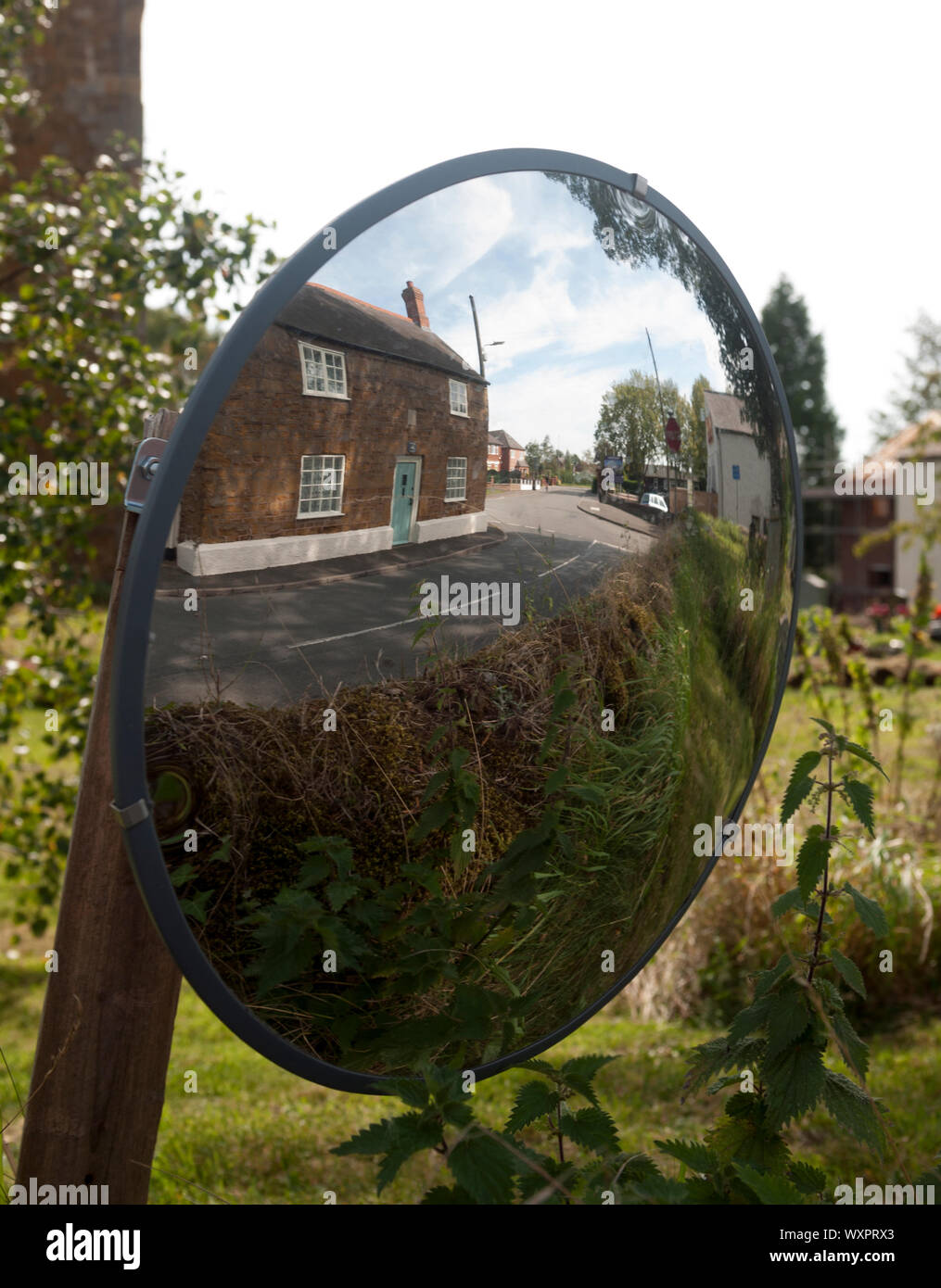 Una superficie convessa la sicurezza stradale specchio in Tilton sul borgo collinare, Leicestershire, England, Regno Unito Foto Stock