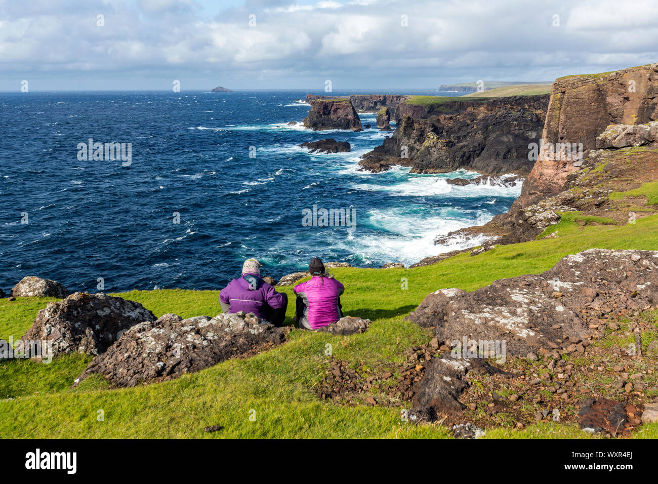 Coppia di donne che cercano le scogliere paesaggio nella penisola Northmavine, Continentale, Shetland, Scotland, Regno Unito Foto Stock