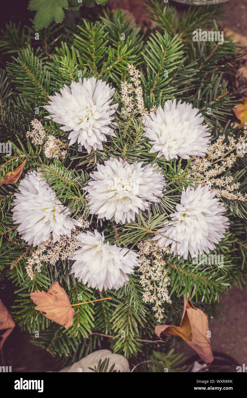 Ghirlanda di fiori bianchi durante il christian tutti i santi giorni della manifestazione che giace nella tomba nel cimitero Foto Stock