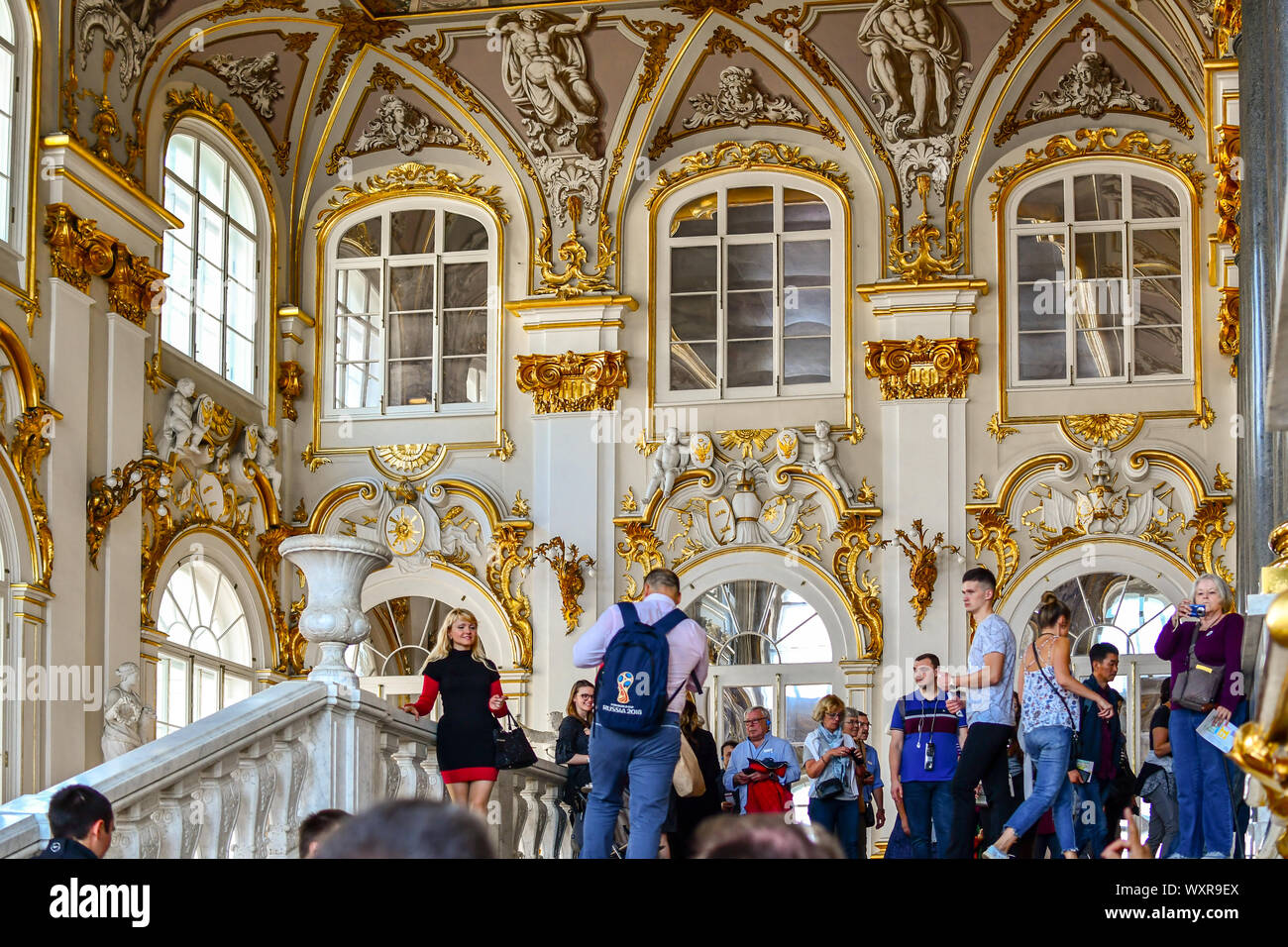 Un bel tour guida attende il suo gruppo all'interno della Giordania scale come turisti a piedi passato all'interno di Palazzo d'inverno del Museo Hermitage in Russia. Foto Stock