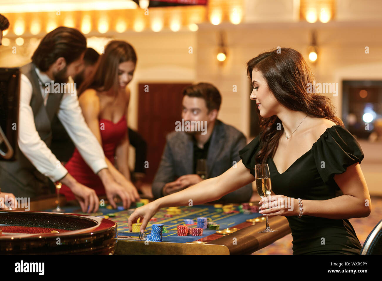 Una giovane donna seduta al tavolo della roulette giocando a poker in un casinò. Foto Stock