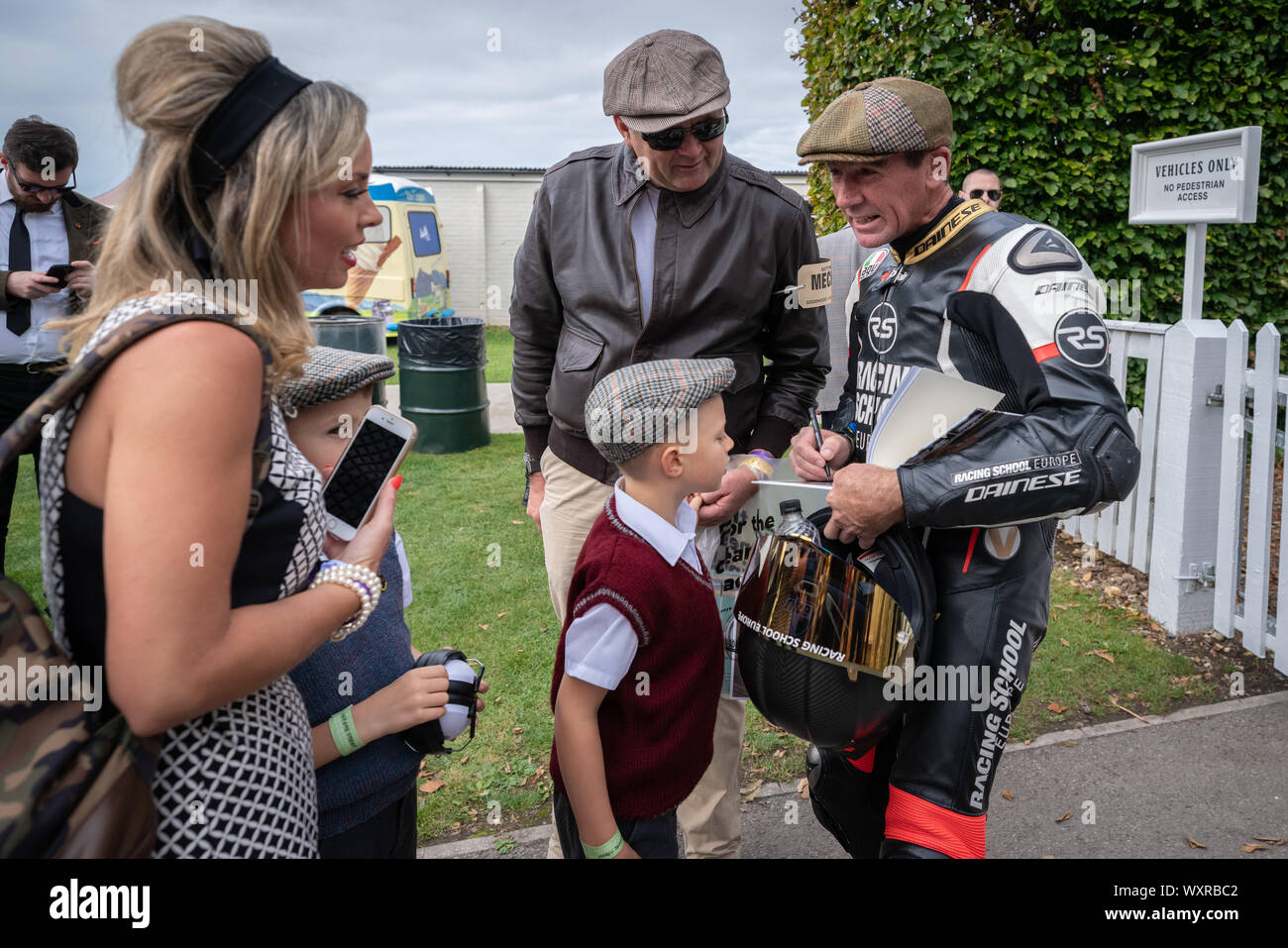 Troy Corser, australiano ex motorcycle road racer, dà autografi per i giovani tifosi durante la vendemmia a tema per Goodwood Festival. Foto Stock