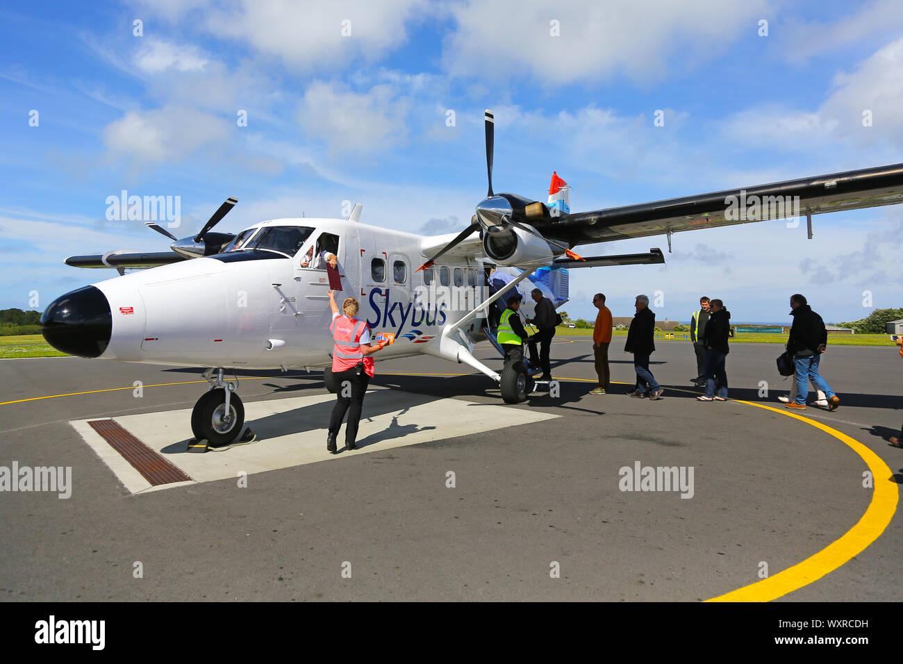 Persone di salire a bordo di un de Havilland Canada DHC-6 Twin Otter, Skybus indicativo di chiamata G-BIHO, a St Marys, aeroporto St Marys, isole Scilly, Cornwall, Regno Unito Foto Stock