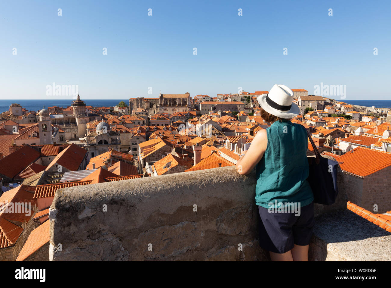 Dubrovnik turistico; una donna che guarda a Dubrovnik città vecchia dalla parete della città a piedi in estate, Stari Grad,( Dubrovnik Città Vecchia ), Croazia Europa Foto Stock