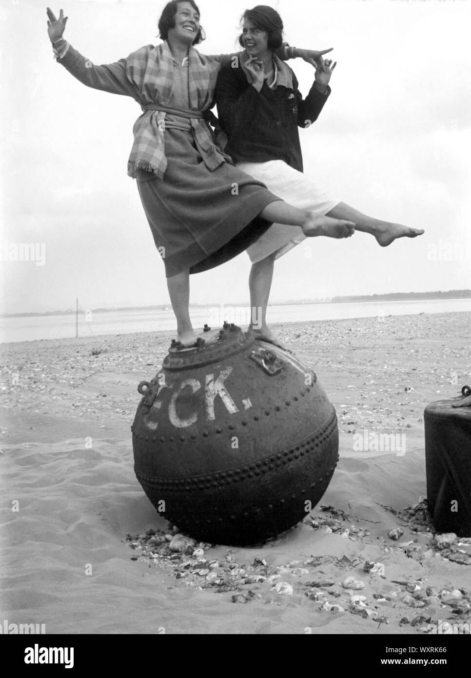 AJAXNETPHOTO. 1920-30S (circa). Posizione sconosciuta, Inghilterra. - Mare snapshot - Due giovani donne pongono per la fotocamera in piedi su un relitto boa su una spiaggia. fotografo:sconosciuto © IMMAGINE DIGITALE COPYRIGHT VINTAGE AJAX Picture Library Fonte: AJAX FOTO VINTAGE COLLEZIONE REF:()AVL PEO 182303 0474 Foto Stock