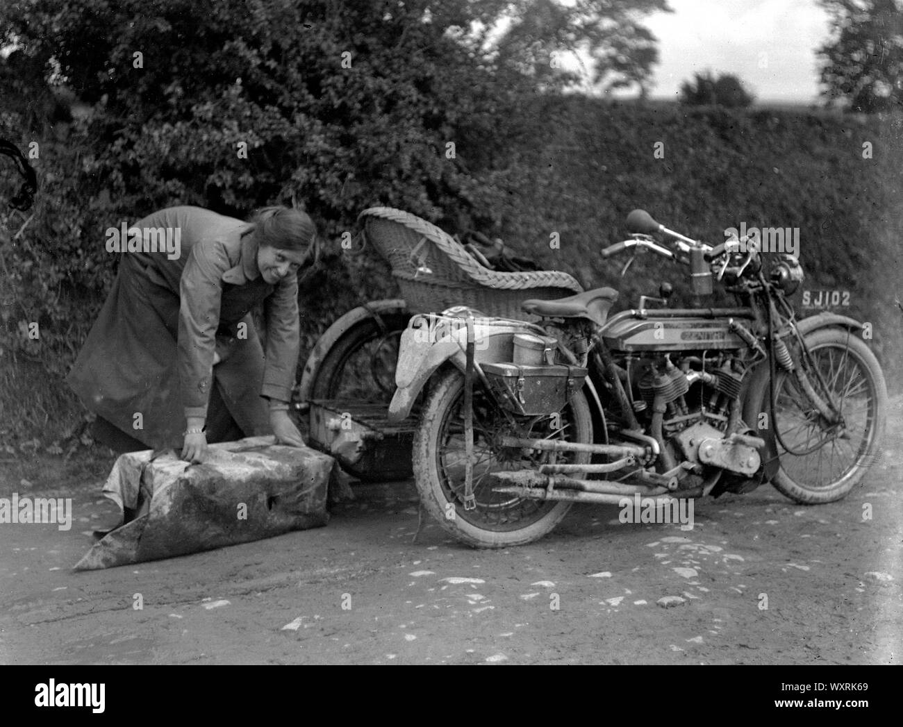AJAXNETPHOTO. 1910 (circa). In Inghilterra. - TOURING in motocicletta - una signora prepara un pacchetto di riporre sulla parte posteriore di un sidecar di vimini; la moto è una ZENITH. fotografo:sconosciuto © IMMAGINE DIGITALE COPYRIGHT VINTAGE AJAX Picture Library Fonte: AJAX FOTO VINTAGE COLLEZIONE REF:()AVL TRA MBIKE JB 80201 54 Foto Stock