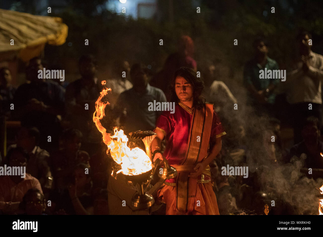 Un giovane sacerdote pienamente impegnata a fare la preghiera della sera a Varanasi Foto Stock