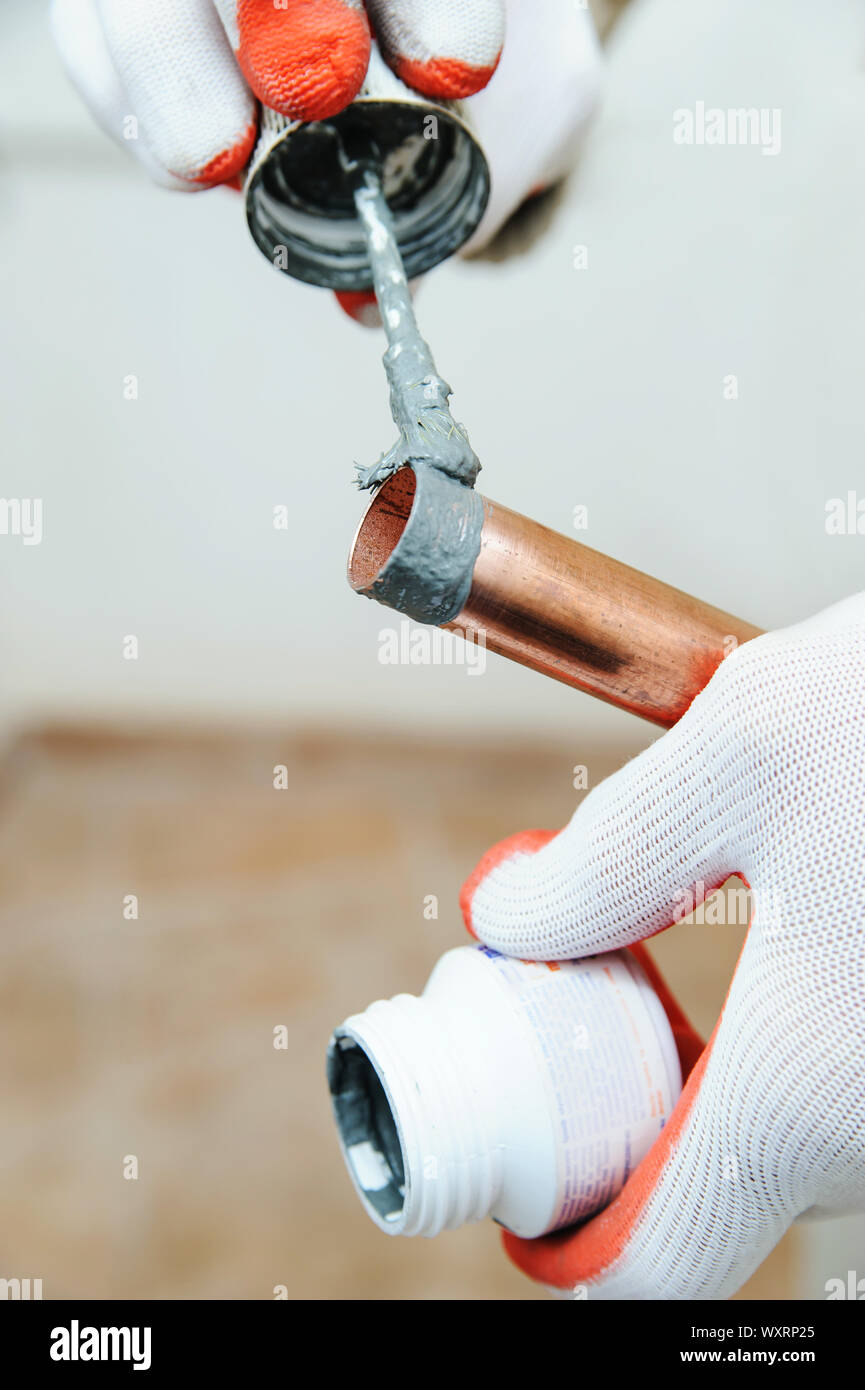 Un lavoratore è applicare il flusso per l'esterno del tubo di rame. Foto Stock