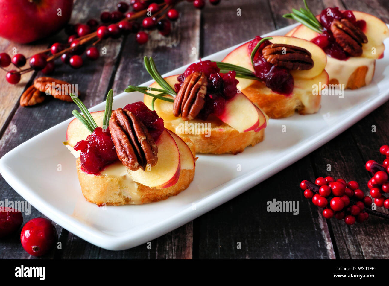 Antipasti Crostini con mele, Cranberries, Brie e le noci pecan. Chiudere su un piatto di portata contro uno sfondo di legno. Foto Stock