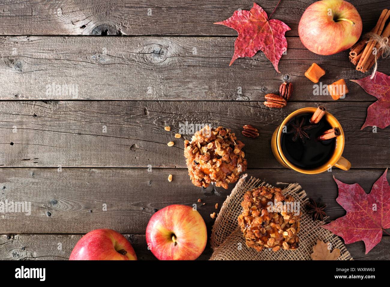 Angolo di autunno confine con apple muffin al caramello e bevanda calda. Vista superiore della tabella sulla scena di un legno rustico sfondo. Copia dello spazio. Foto Stock