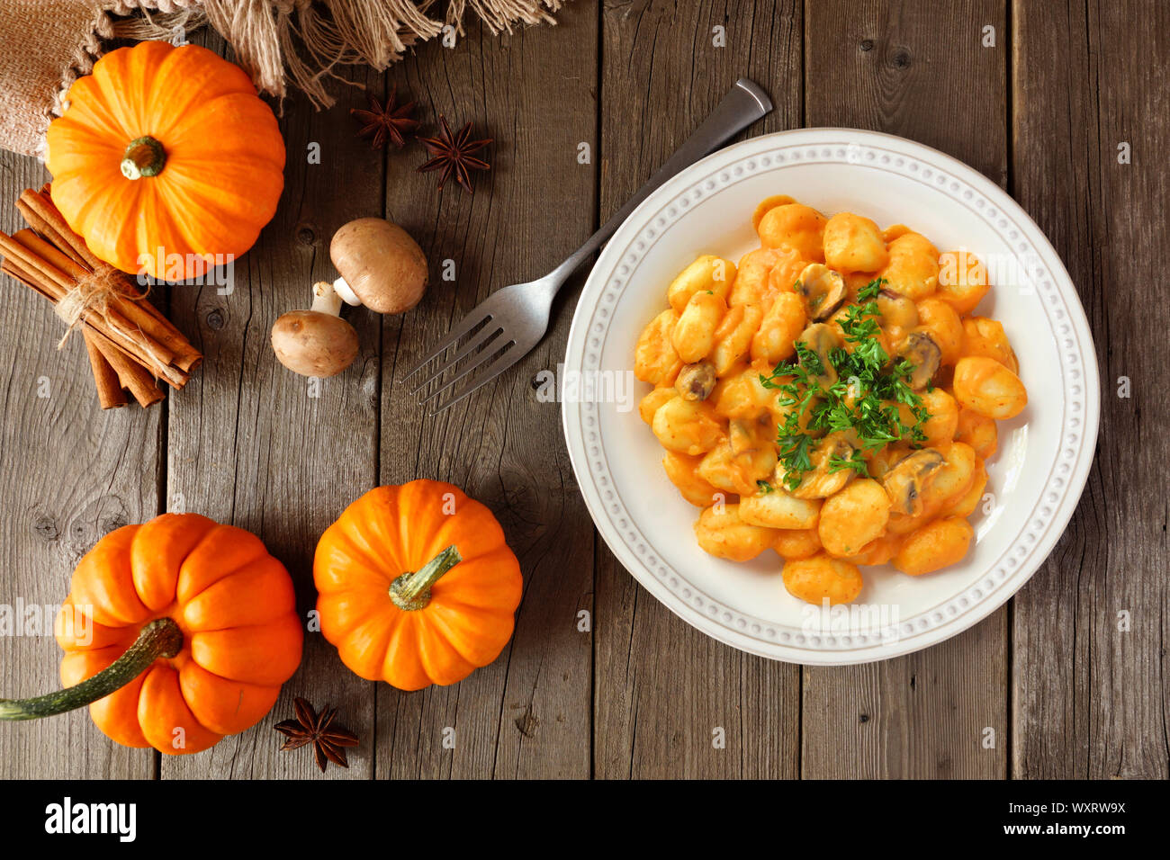 Gnocchi con una zucca, crema di funghi salsa. Pasto d'autunno. Vista sopra la tabella di scena sul fondo in legno. Foto Stock