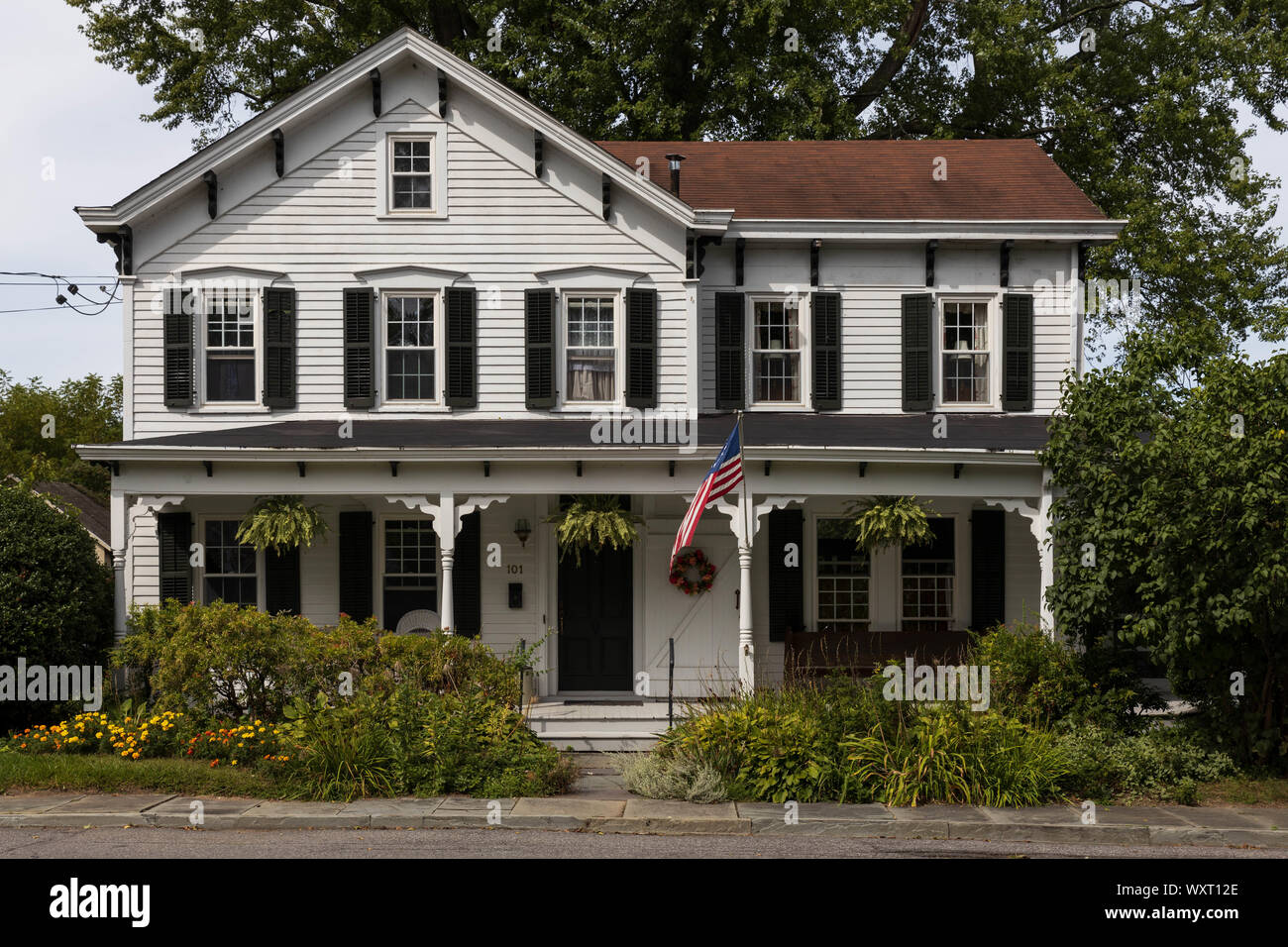 New Paltz, New York - 6 Settembre 2019: bandiera americana vola nella parte anteriore del grande casa tradizionale in zona tranquilla Foto Stock