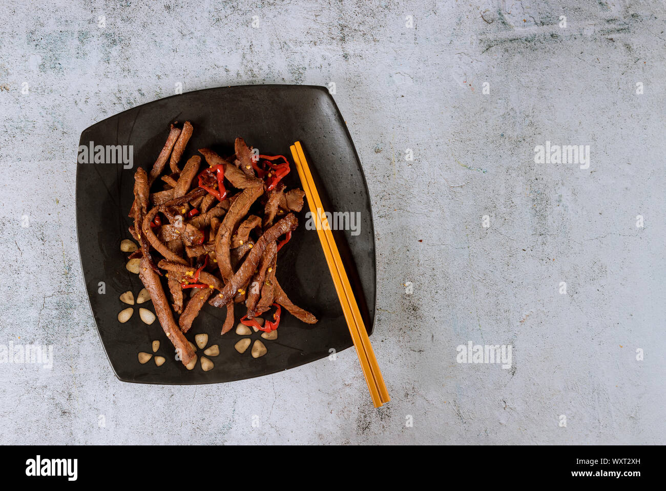 Asian teriyaki manzo con peperoncino e chopstick su piastra nera. Foto Stock