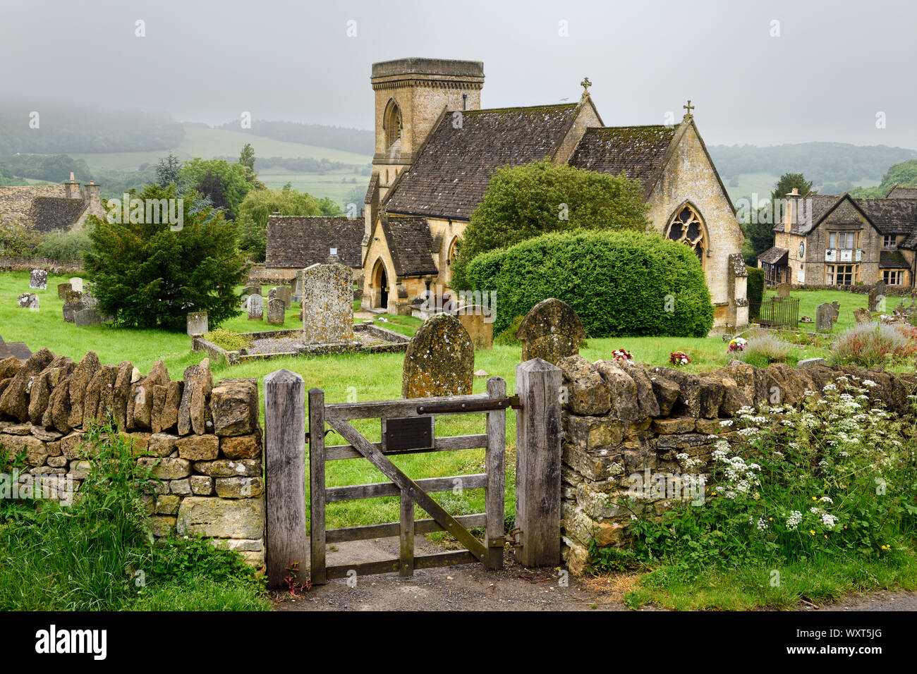 San Barnaba chiesa anglicana con il cimitero e il muro di pietra porta umido in condizioni di tempo piovoso in Snowshill Cotswold Inghilterra Foto Stock