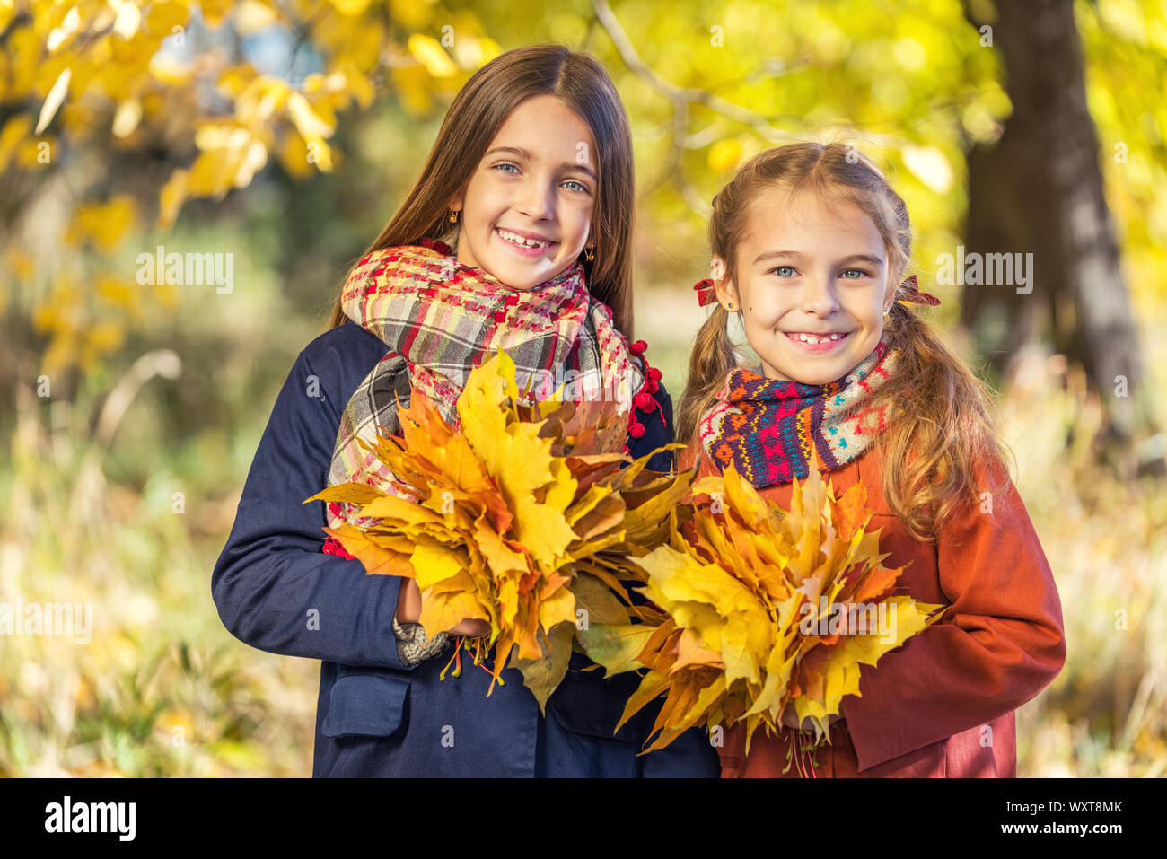 Due graziosi sorridente 8 anni le ragazze in posa insieme in un parco su una soleggiata giornata autunnale. Foto Stock