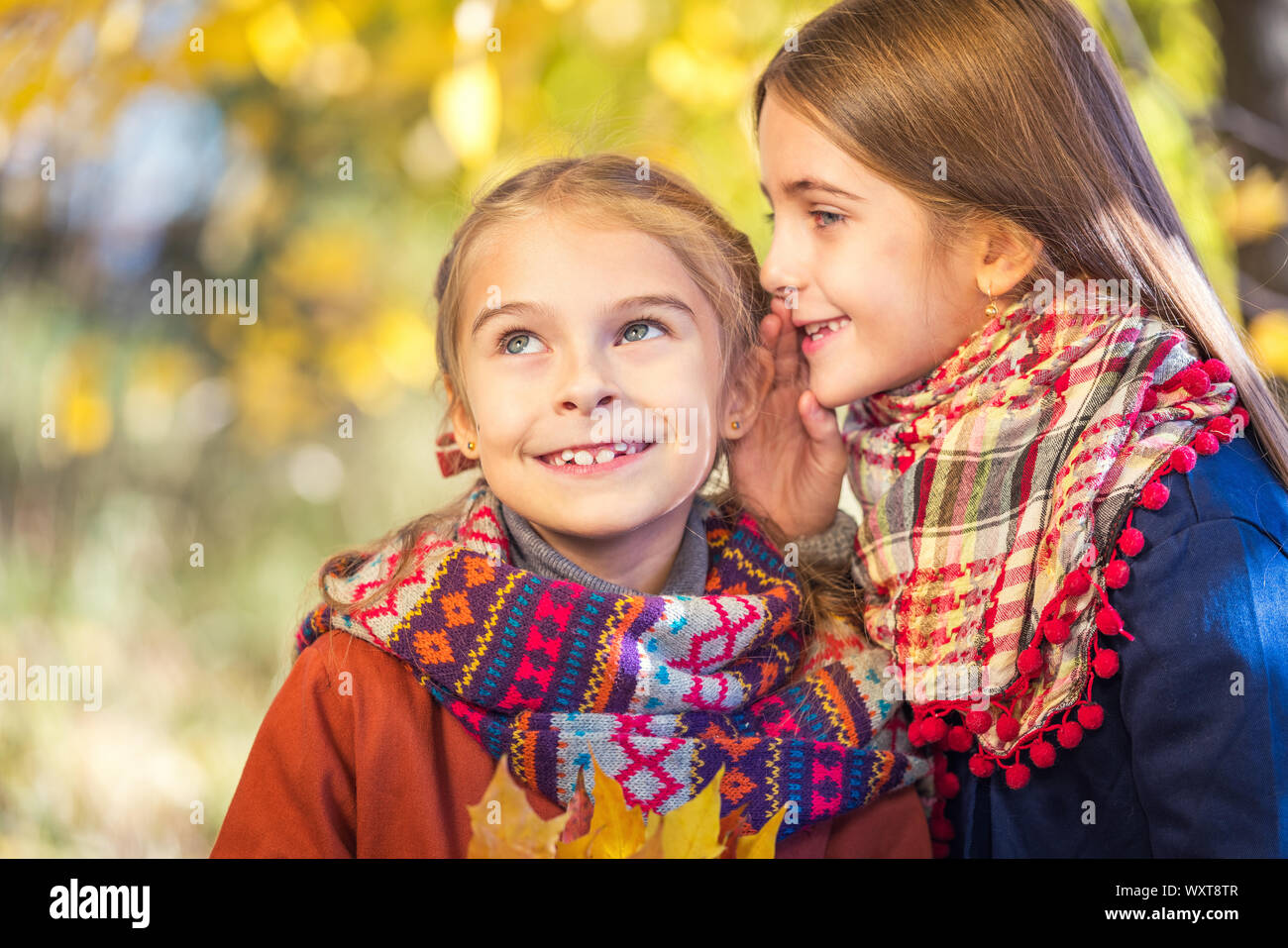 Due graziosi sorridente 8 anni le ragazze in chat in un parco su una soleggiata giornata autunnale. Foto Stock